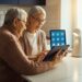 Beste slimme apparaten voor ouderen in gebruik: senior en mantelzorger bekijken een tablet aan de keukentafel met slimme verlichting op de achtergrond