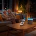Seniorenkoppel ontspant in woonkamer met dimbare slimme verlichting en eenvoudige afstandsbediening – een voorbeeld van slimme verlichting voor ouderen voor extra comfort in huis.