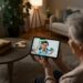 Een oudere vrouw in een videogesprek met een fysiotherapeut op een tablet, een voorbeeld van AI in de zorg die comfort en moderne zorgtechnologie benadrukt.