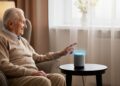Een oudere persoon gebruikt een virtuele assistent in een gezellige woonkamer om dagelijkse taken eenvoudiger te maken.